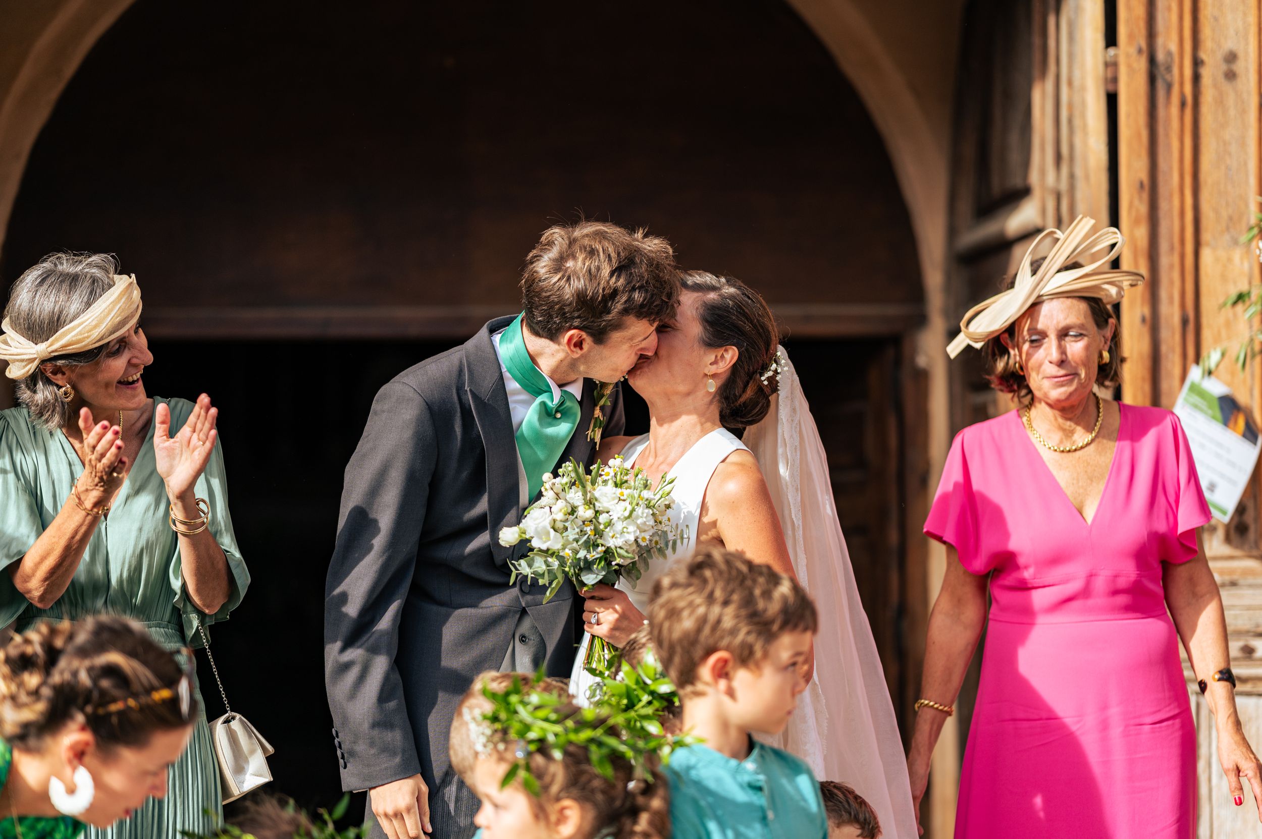 A wedding ceremony moment under an archway with guests looking on.