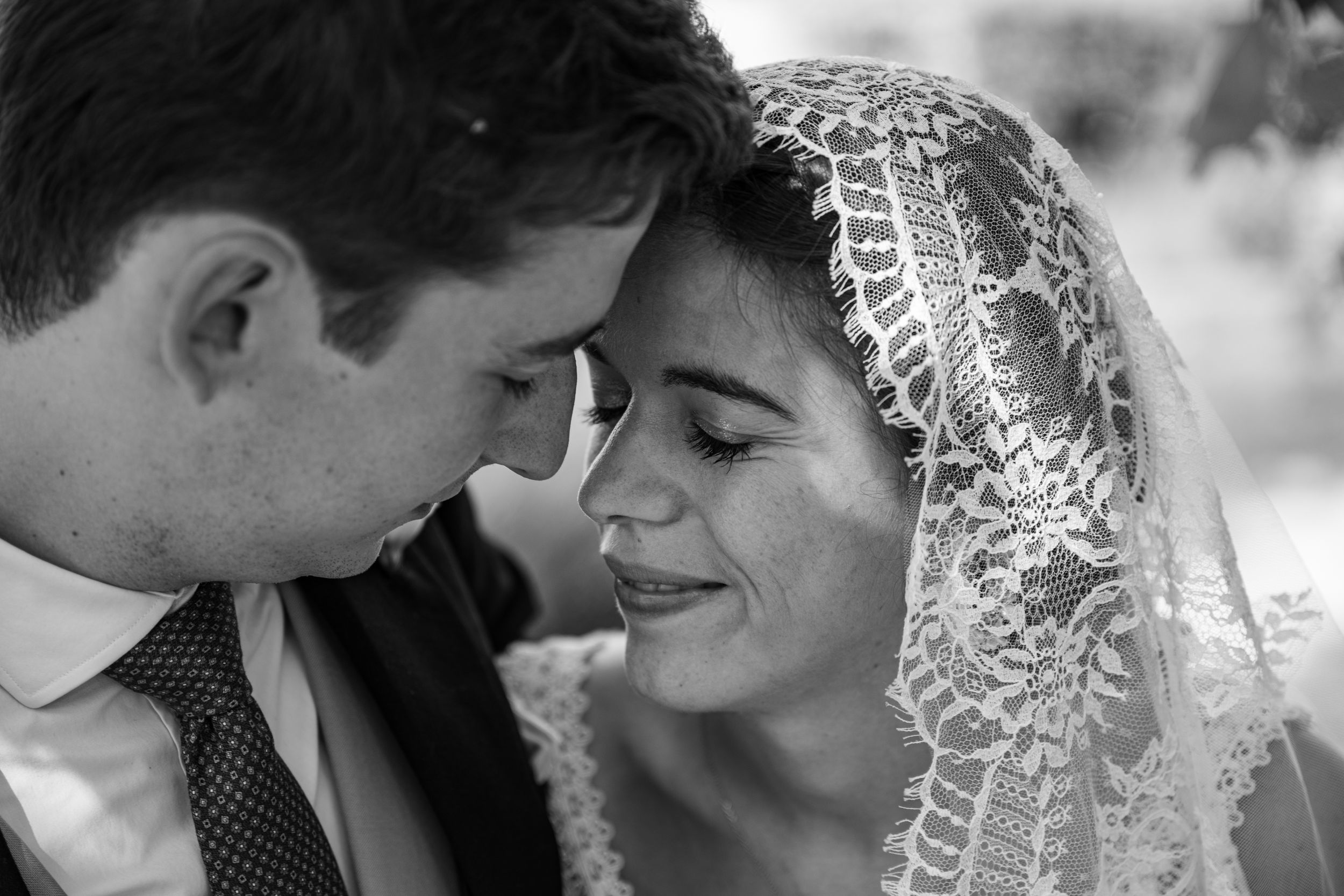 An intimate black and white wedding portrait showing a tender moment between newlyweds.