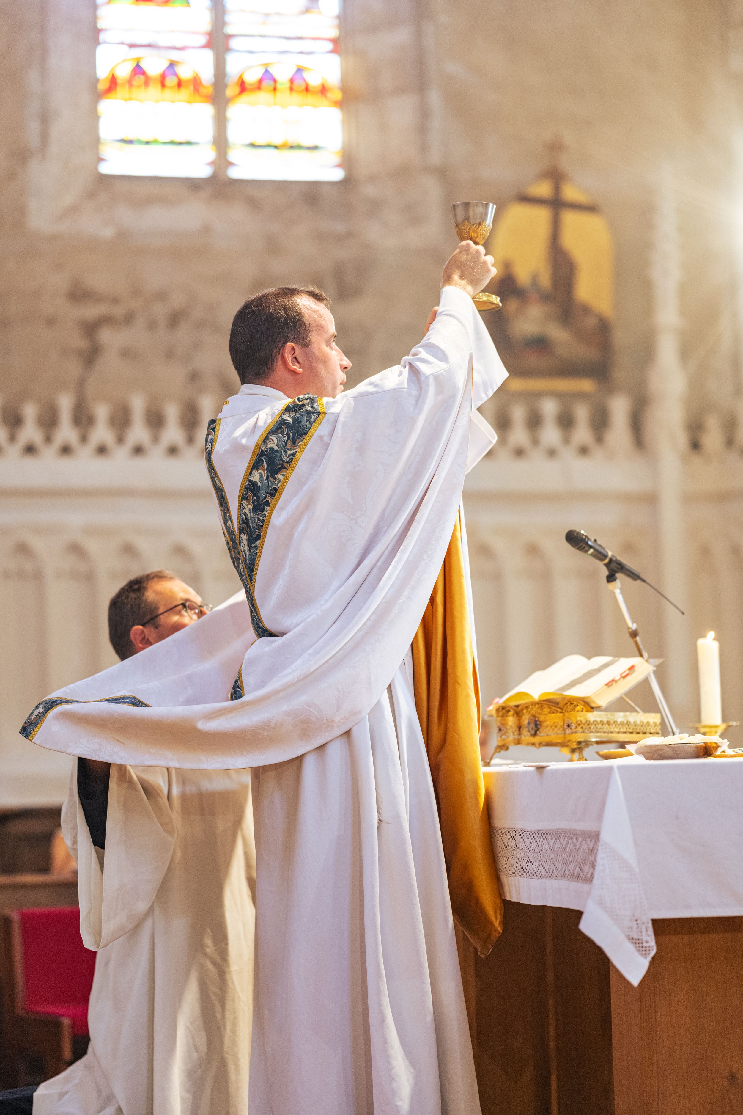A priest raises the communion chalice during a Catholic wedding ceremony.