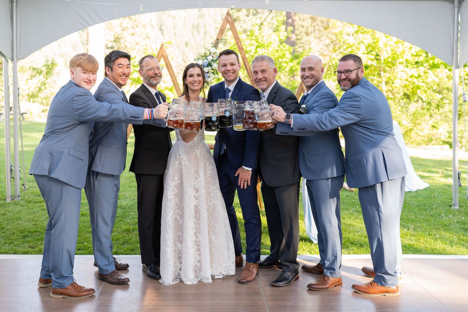 Wedding party celebrates with champagne toast under outdoor tent.
