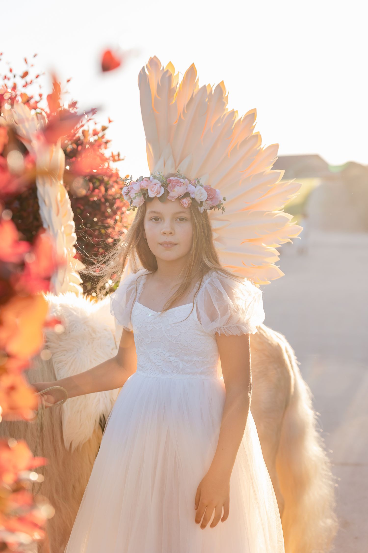A white dress and floral crown create an ethereal scene against sunset lighting.