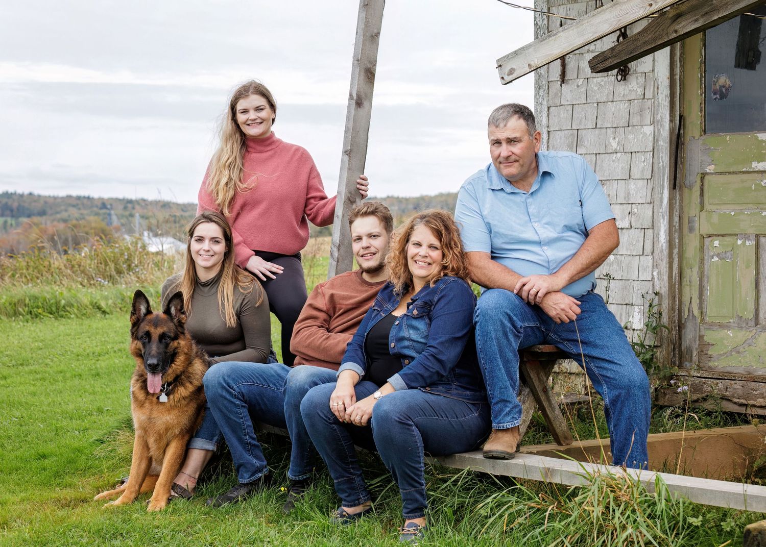 A photo of a happy family relaxing in front of their old beach shed.