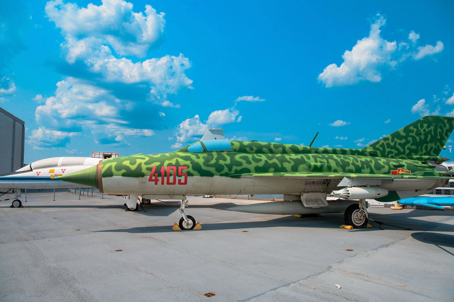 A sleek tan-colored military jet aircraft parked at an outdoor display area.