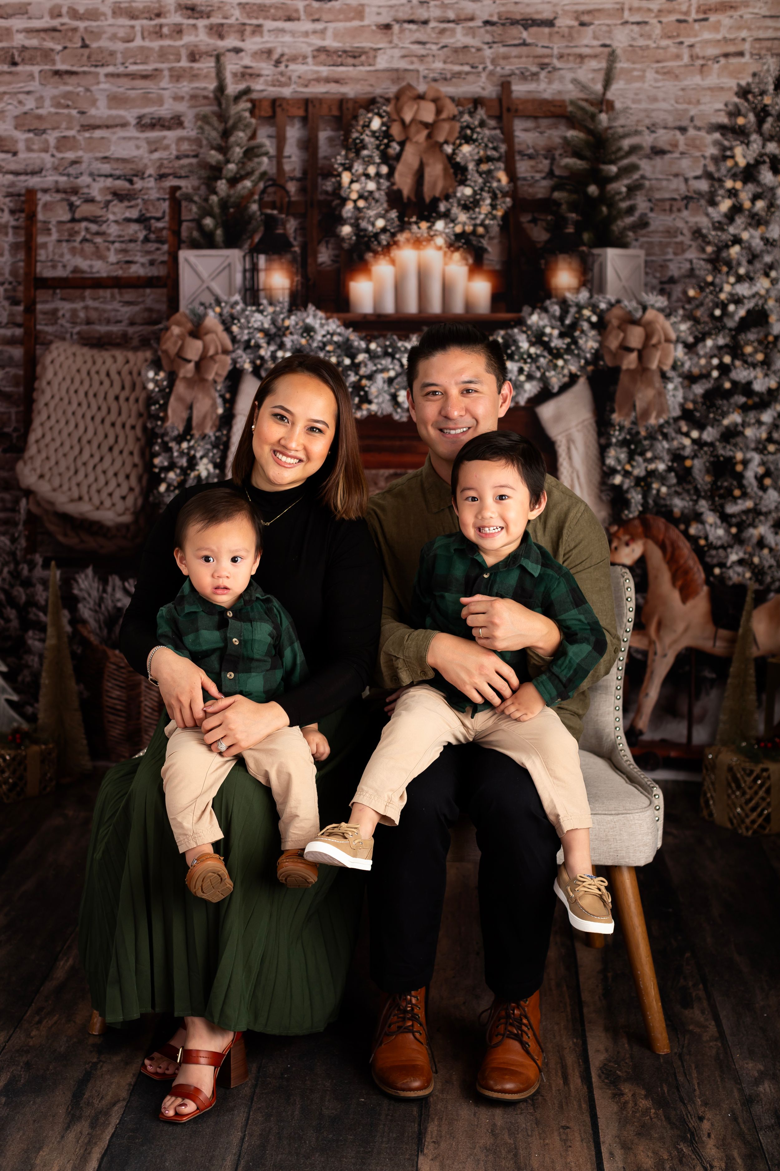 Holiday family portrait with coordinated outfits in front of a Christmas fireplace setting.