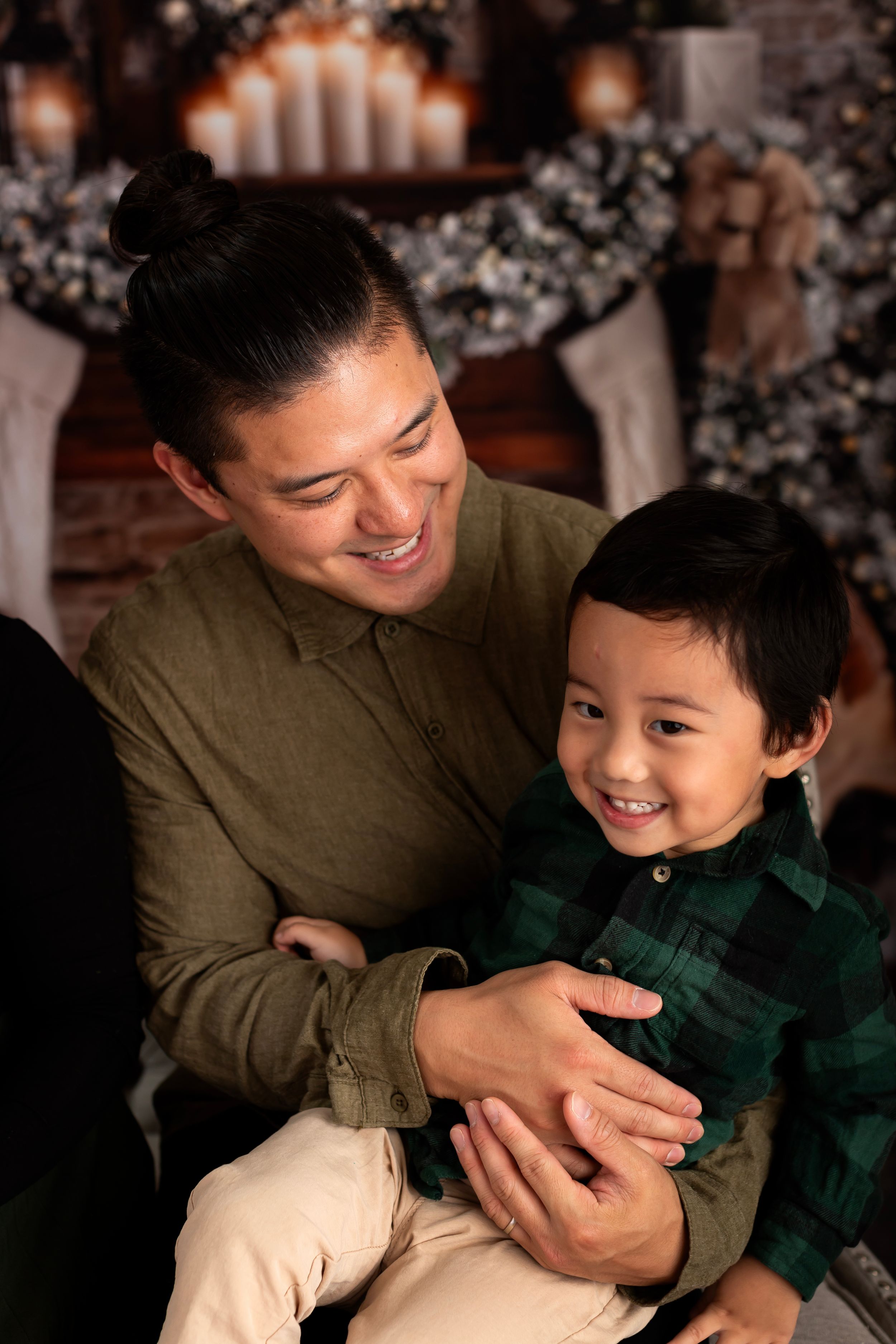 A heartwarming family moment captured in front of a cozy Christmas backdrop with glowing candles and decorations.