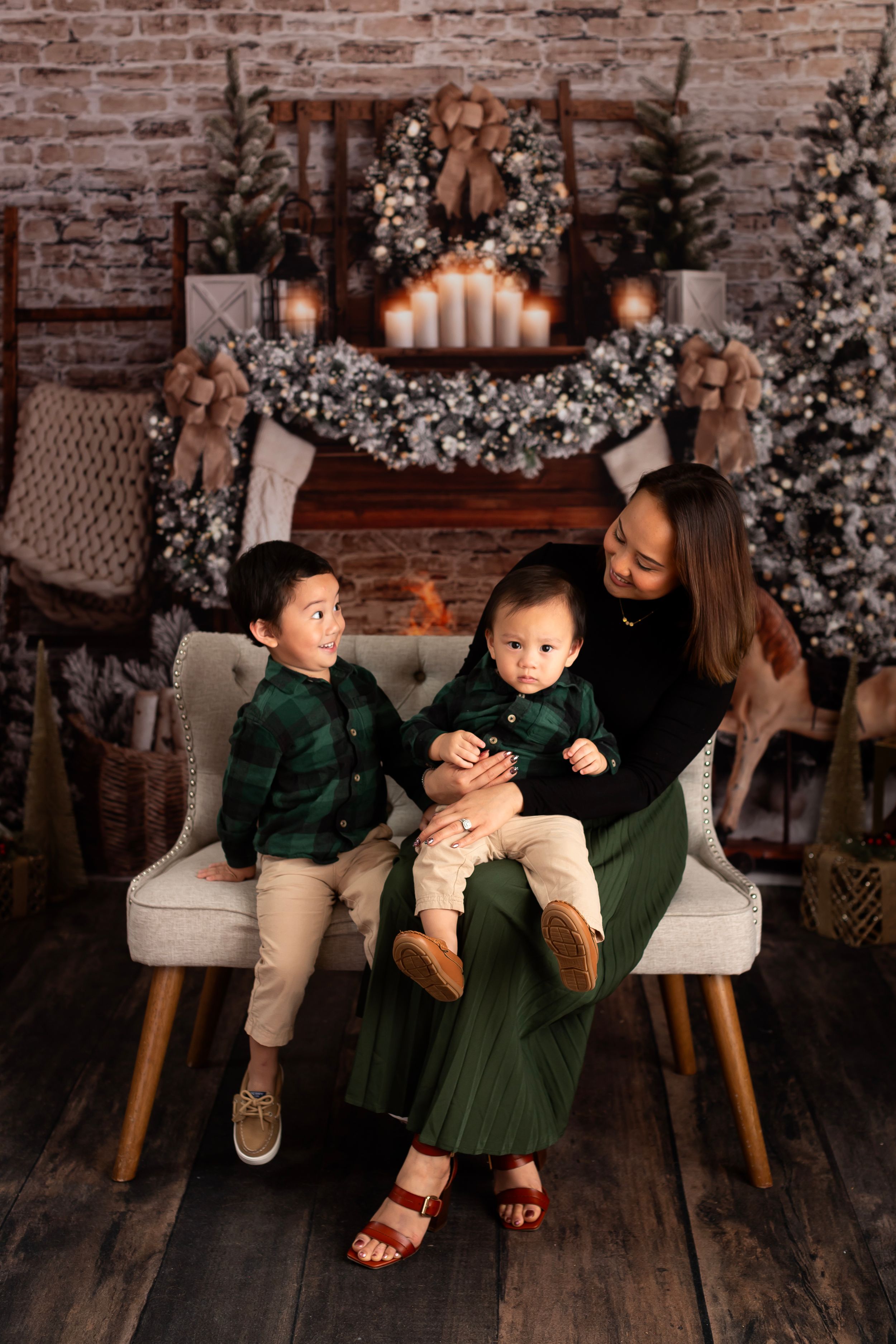 Candid family moment on a gray chair against a decorated Christmas backdrop with twinkling lights.