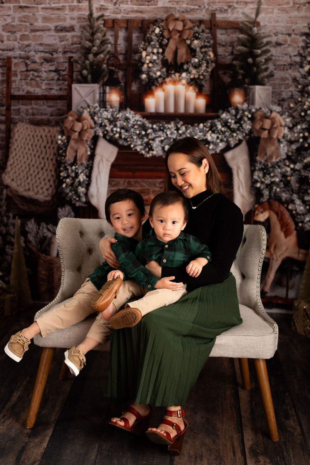 Beautiful holiday portrait featuring a modern chair and festive Christmas mantel with candles and garland.