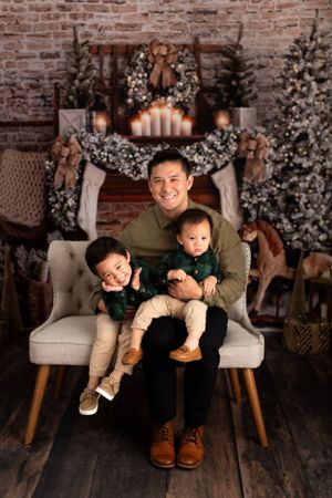 Festive holiday portrait with Christmas decorations, flocked trees, and a beautifully lit brick backdrop.