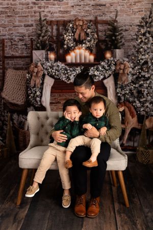Intimate family moment captured against a Christmas themed backdrop with twinkling lights and decorations.