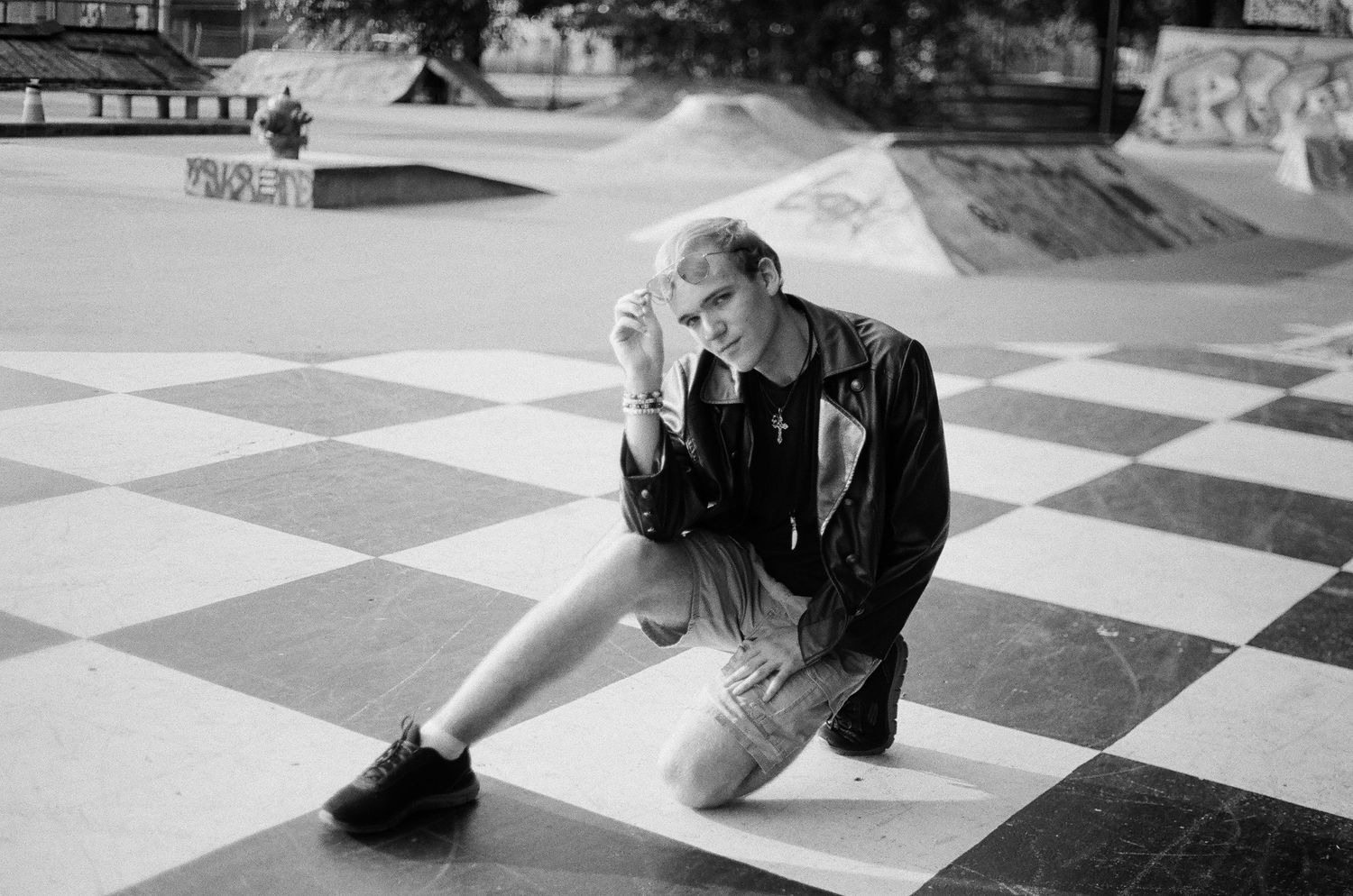 Person lying on a black and white checkered floor in casual attire.