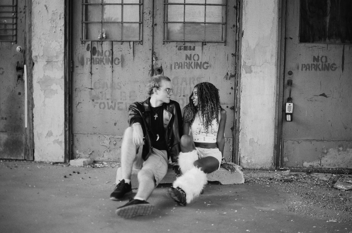 Black and white architectural shot of industrial doorways with graffiti and worn textures.
