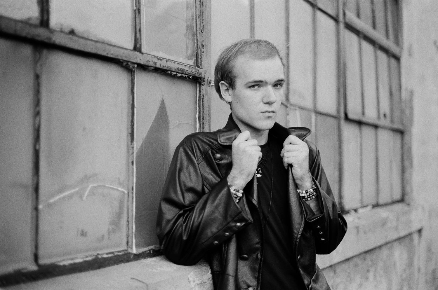 Moody black and white photograph showing someone leaning against a wall.