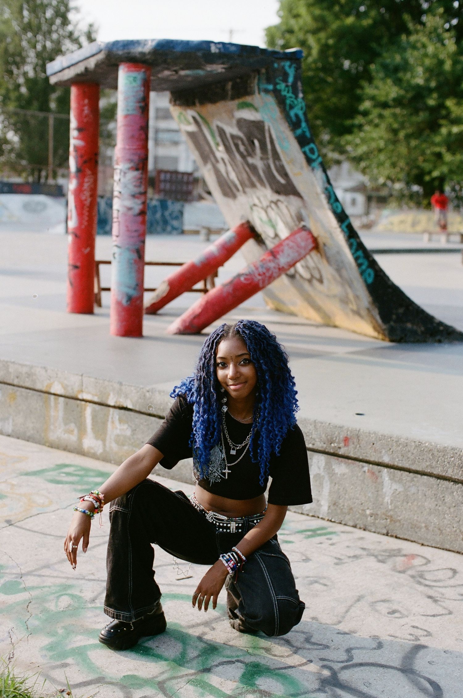 Outdoor fashion photography session at skate park with painted pillars and graffiti.