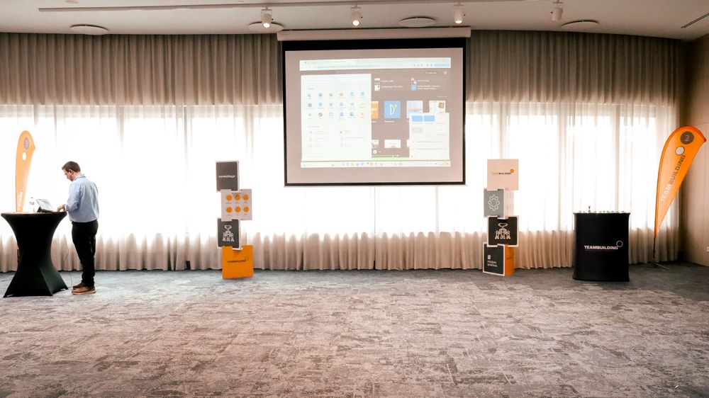 Business presenter standing at podium in conference room with large projection screen displaying data.