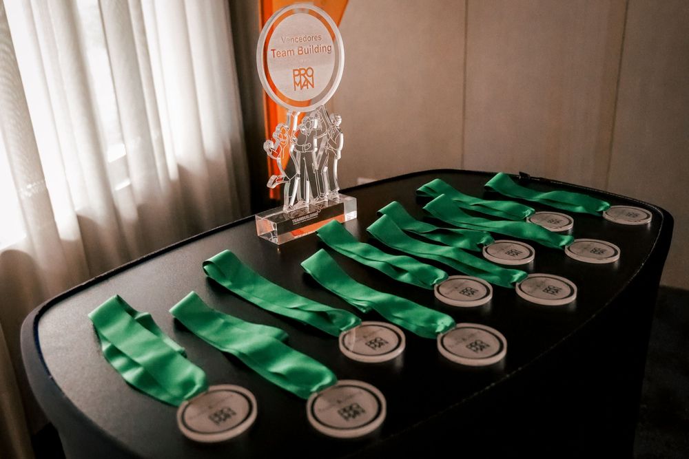Team building awards display with silver medals featuring green ribbons and a crystal trophy on a black table.
