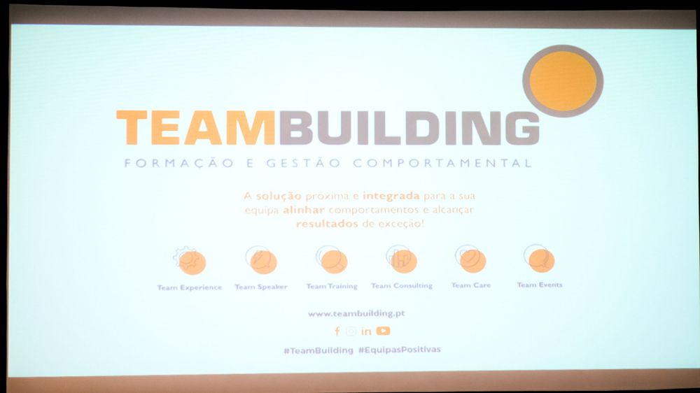 TeamBuilding corporate presentation slide displayed on a large screen in a conference room.