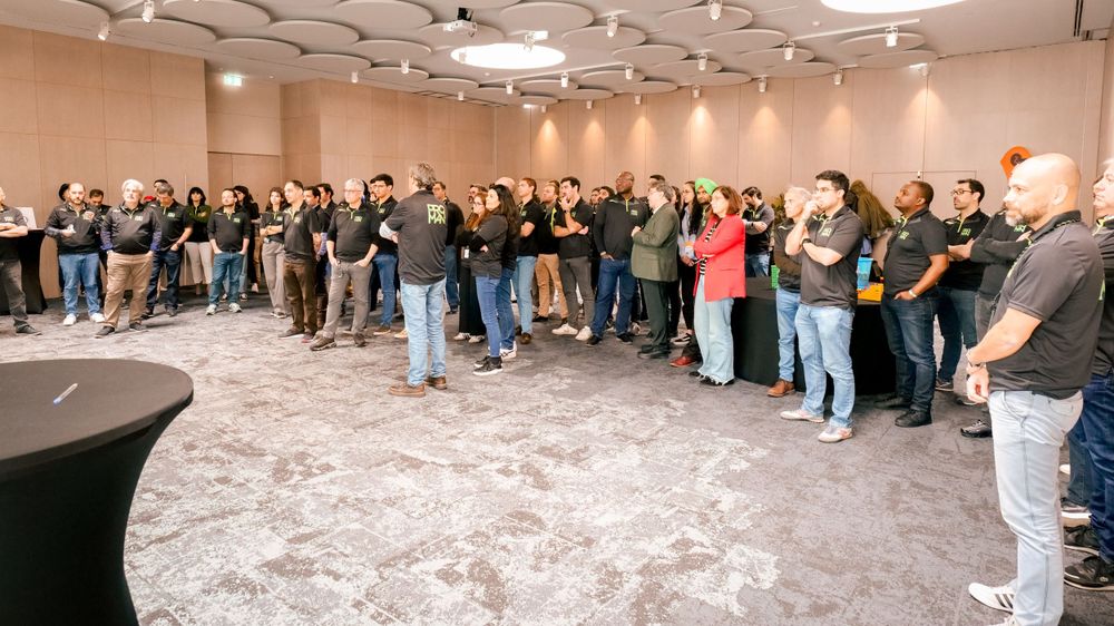 Large group of employees in matching black uniforms gathered in a modern conference room for team building.