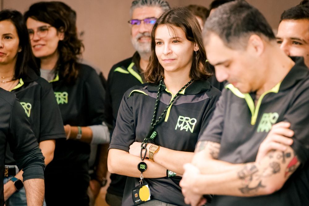 Team members in ProMan black uniforms listening attentively during a corporate team building activity.
