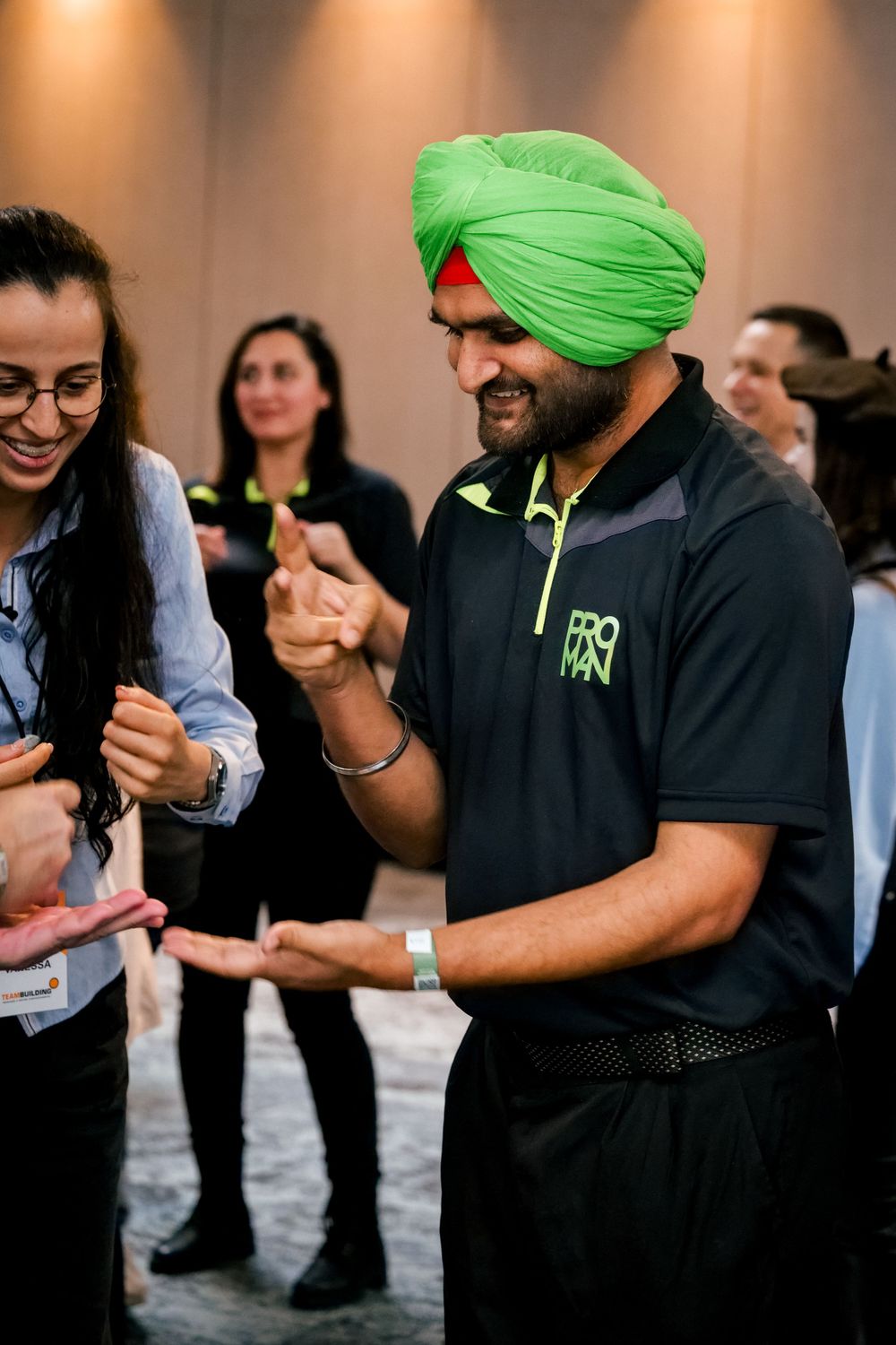 Man wearing a bright green turban participates in an engaging team building activity with colleagues.