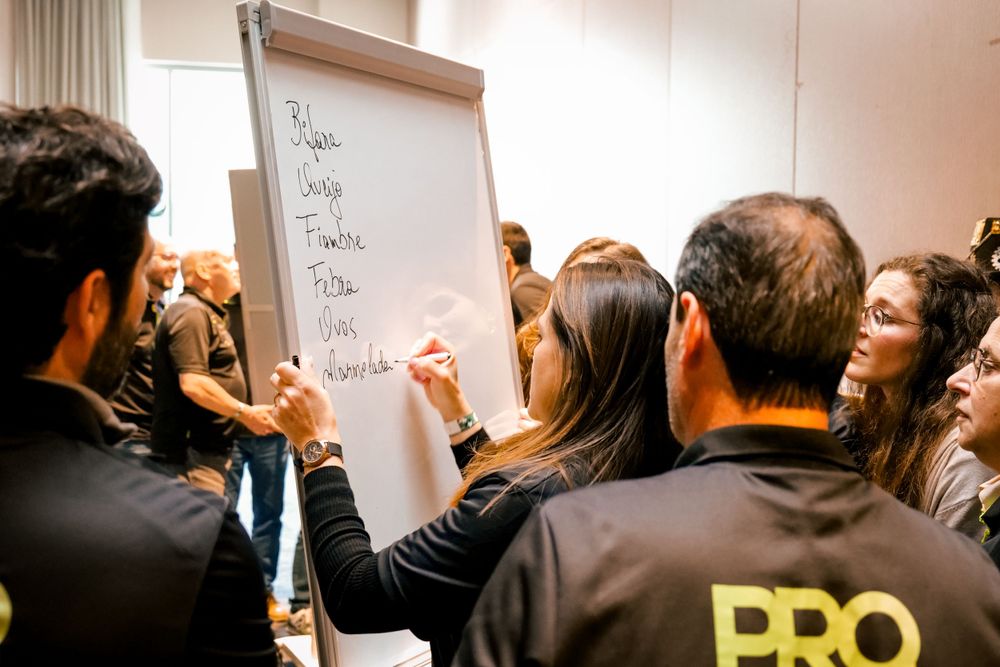 A woman writes on a whiteboard flipchart during a team brainstorming workshop with PRO-branded staff.