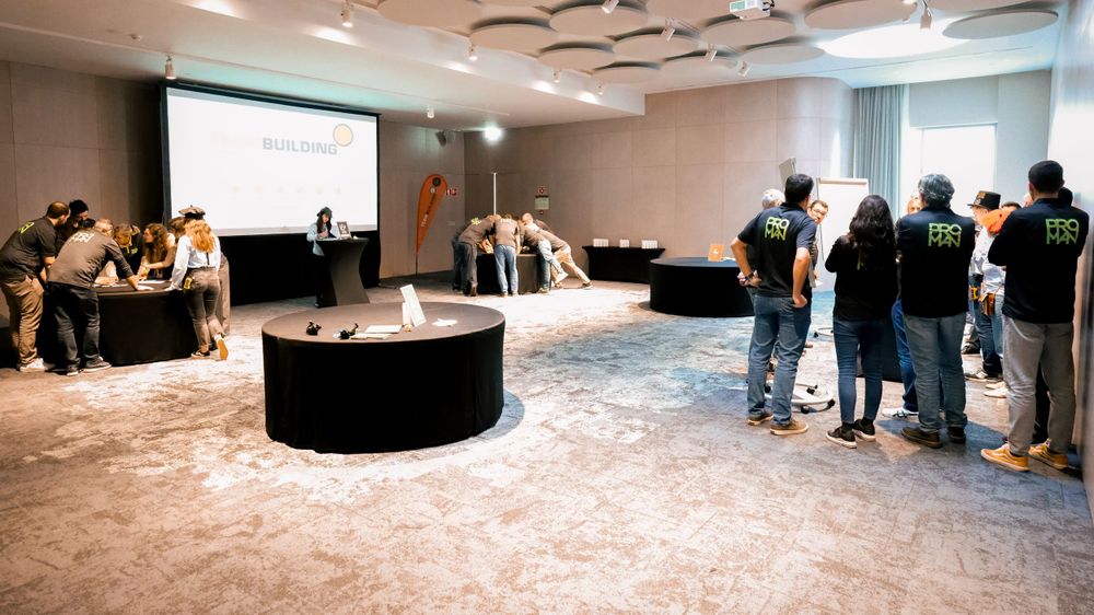 Corporate team building event in a conference room with round tables and a presentation screen.