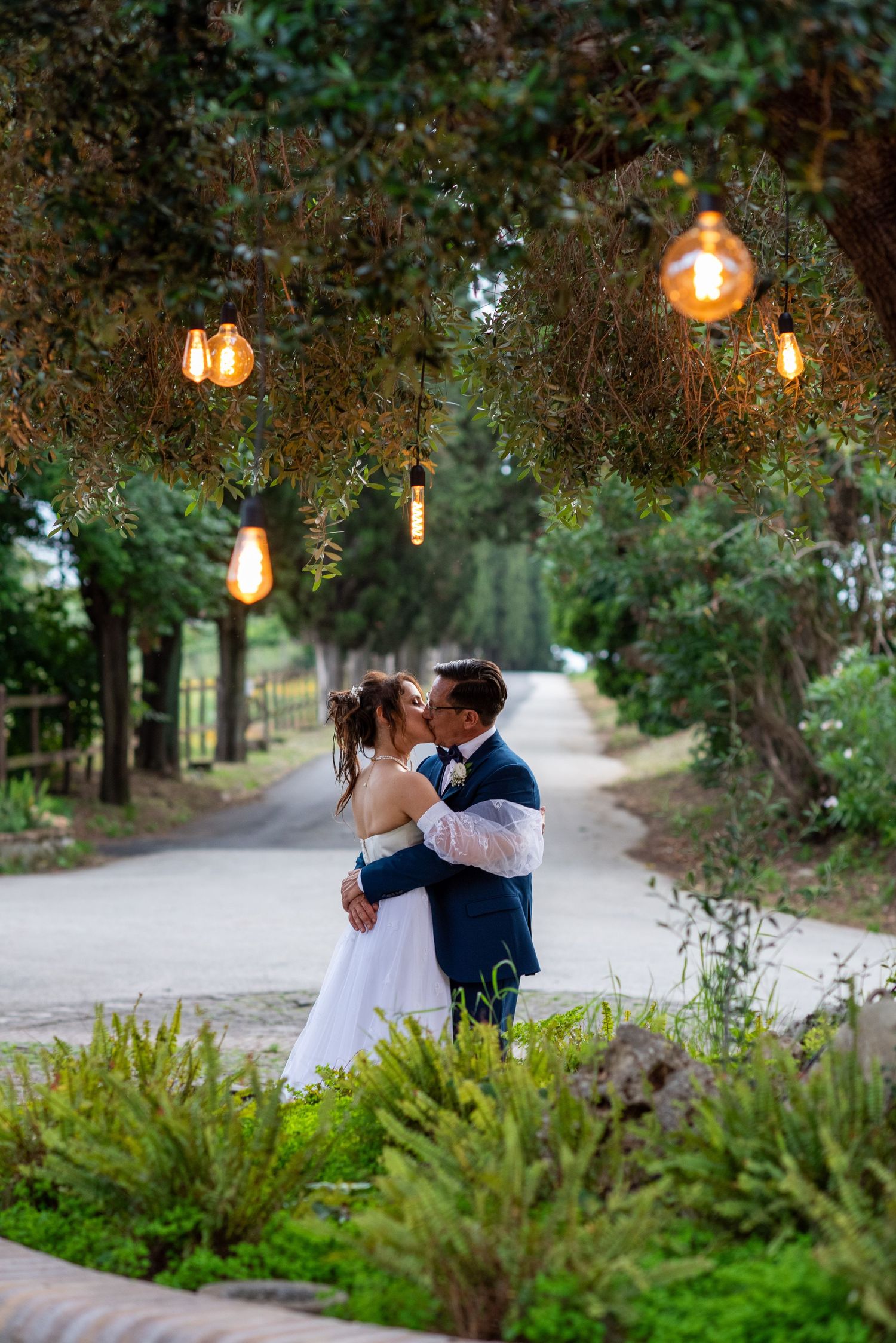 Garden wedding photos with hanging Edison bulbs creating romantic ambiance.