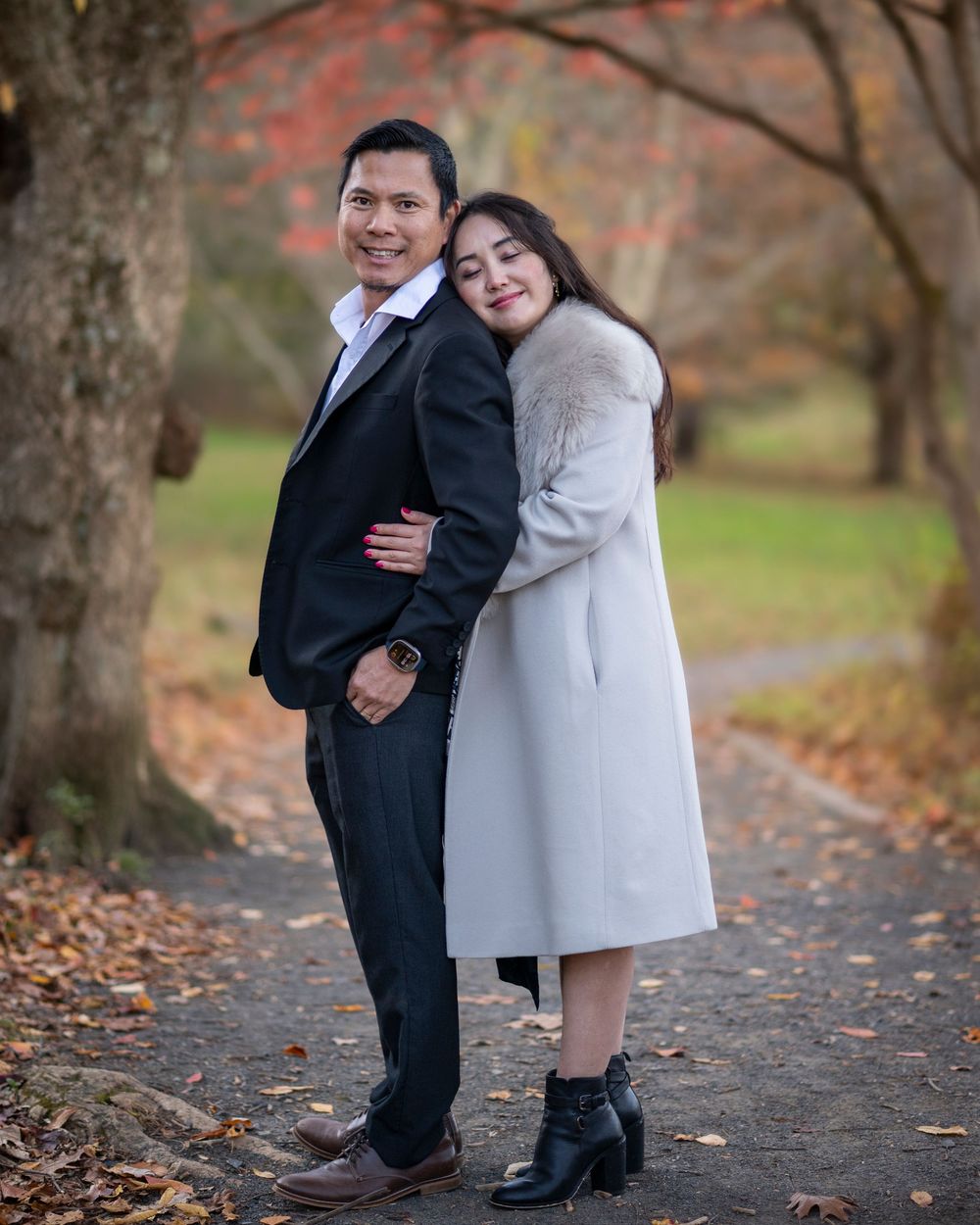 A couple poses elegantly on a park path surrounded by colorful autumn trees.Holmdel Park NJ