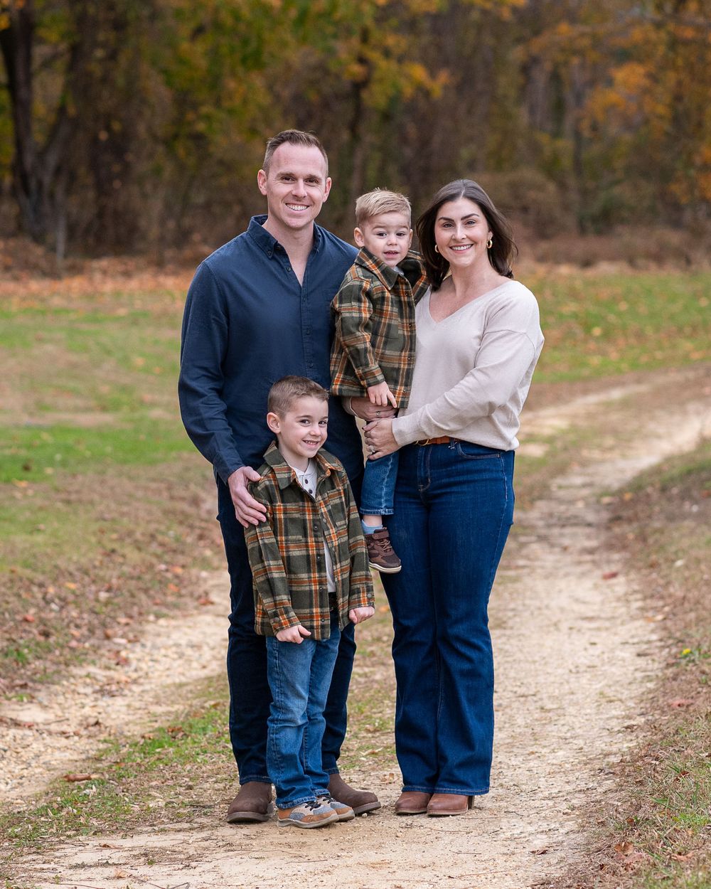 Family of four poses on a dirt path surrounded by colorful autumn foliage.Middletown NJ