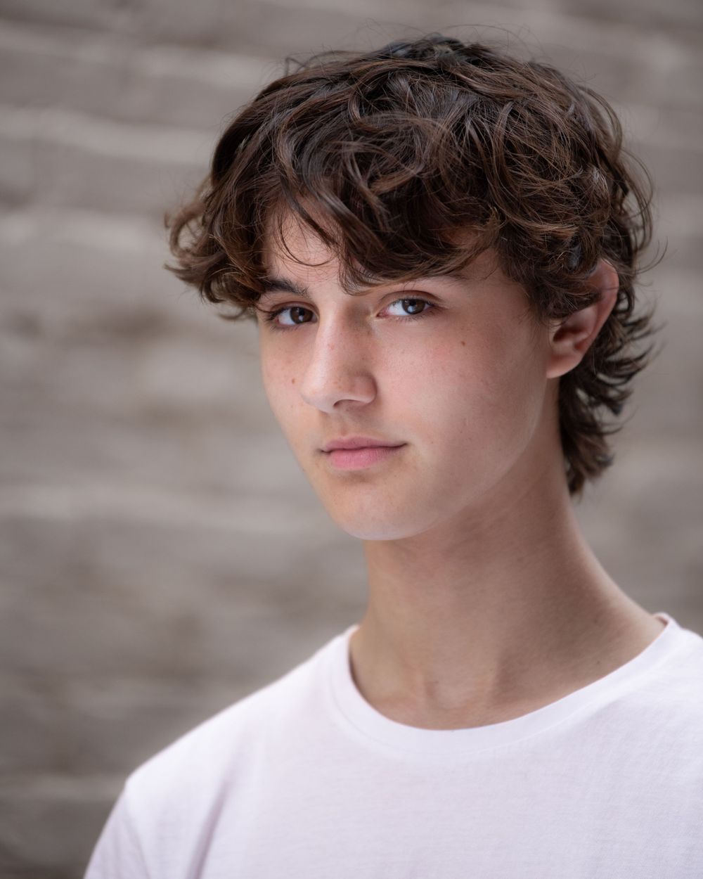 Headshot Portrait of a teen boy in white shirt against brick background in Atlantic Highlands NJ