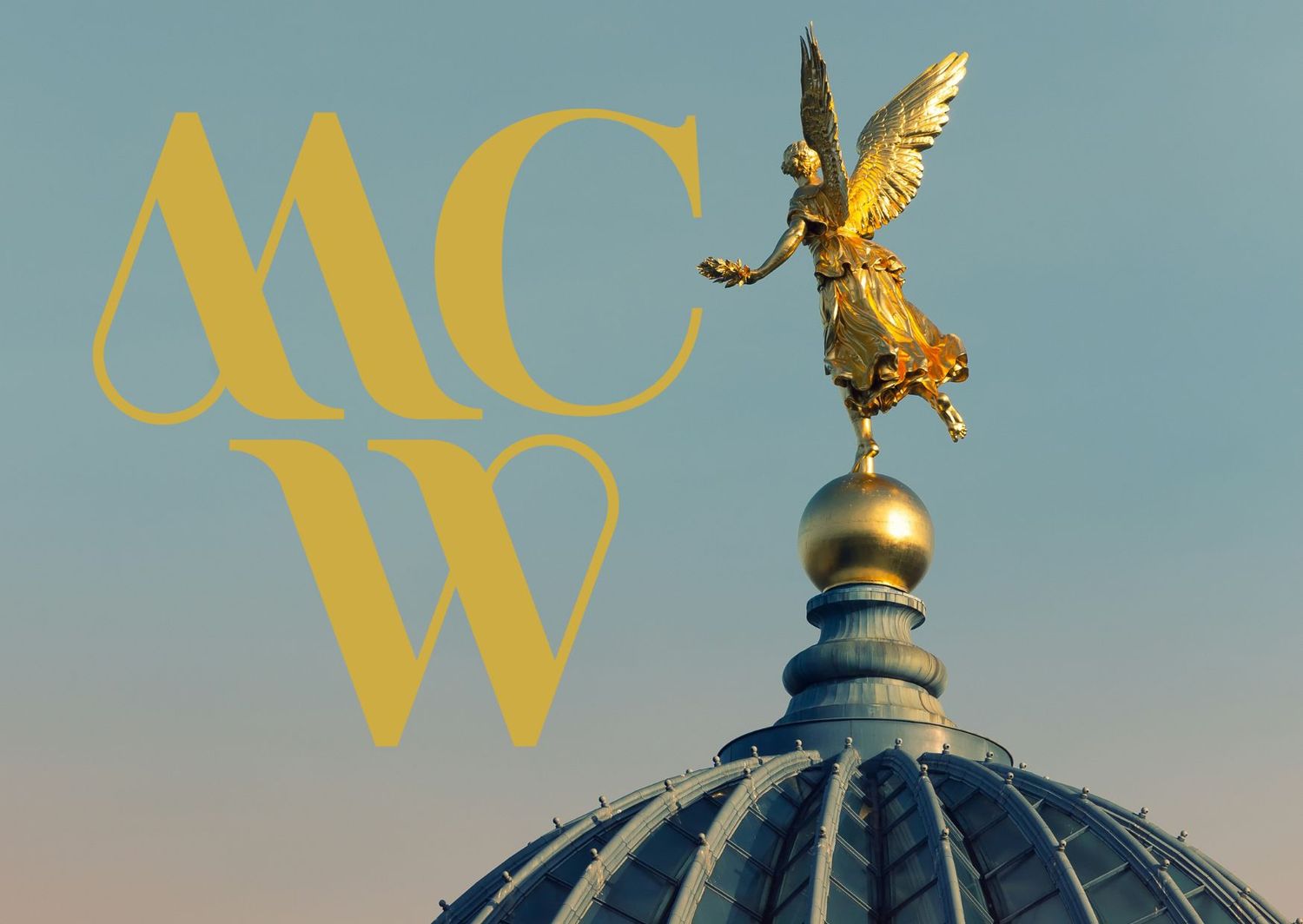 Gold MCW monogram with an ornate angel statue atop a domed architectural element against a blue sky.