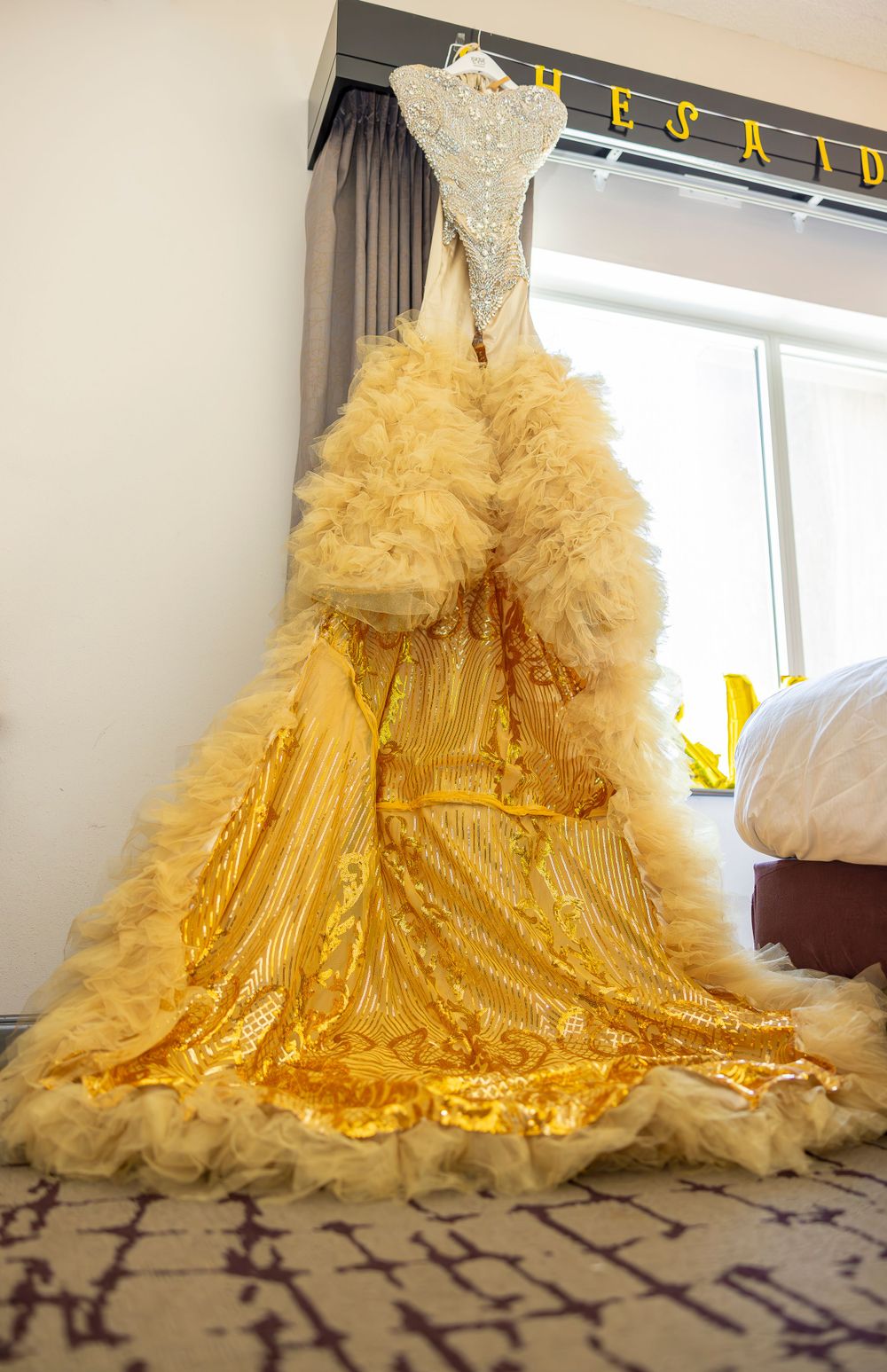 Stunning gold and white wedding gown with tulle skirt displayed on hanger.