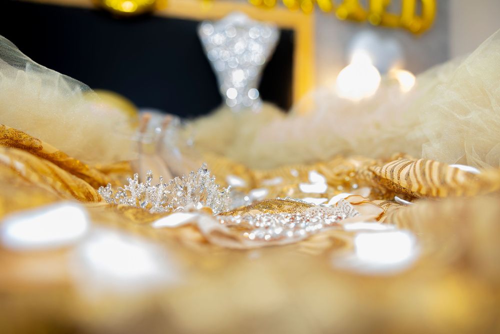 Close up of sparkling wedding accessories and jewelry on gold fabric.