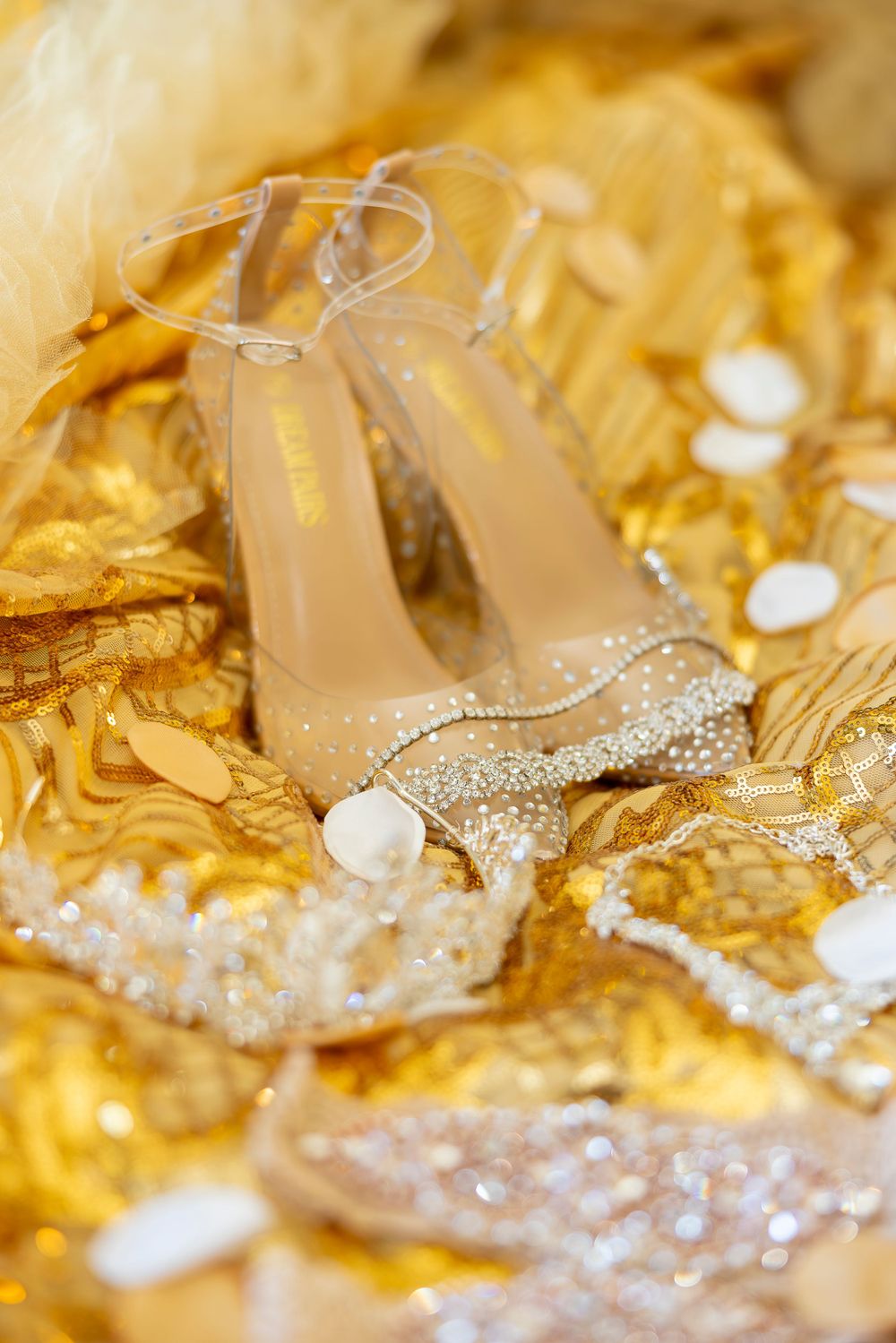 Crystal-embellished nude wedding heels displayed on golden fabric.
