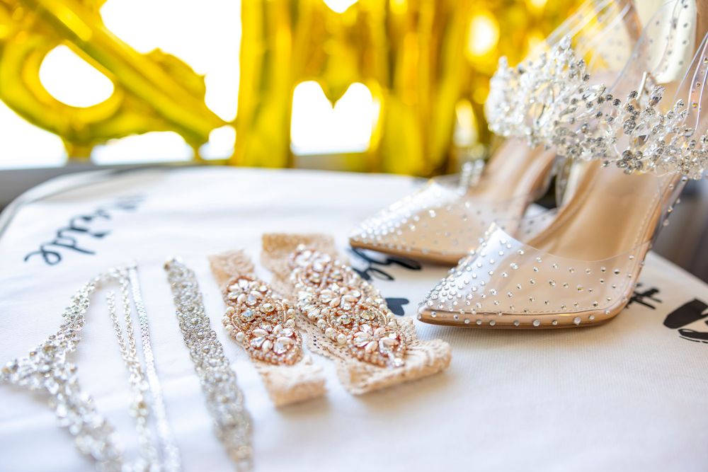 Elegant bridal shoes with crystal embellishments displayed against a glowing golden backdrop.