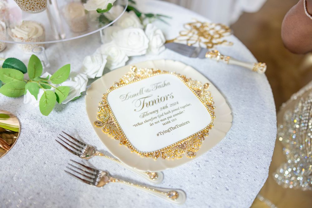 Elegant wedding place setting with gold glitter details and white floral accents.