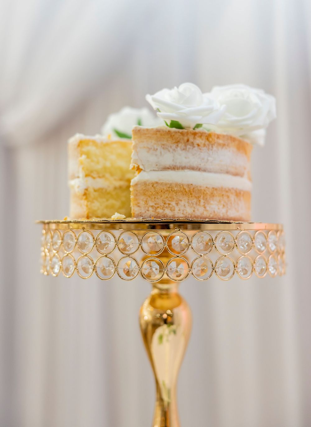 Delicate peach-colored wedding cake slice displayed on an ornate gold crystal cake stand.