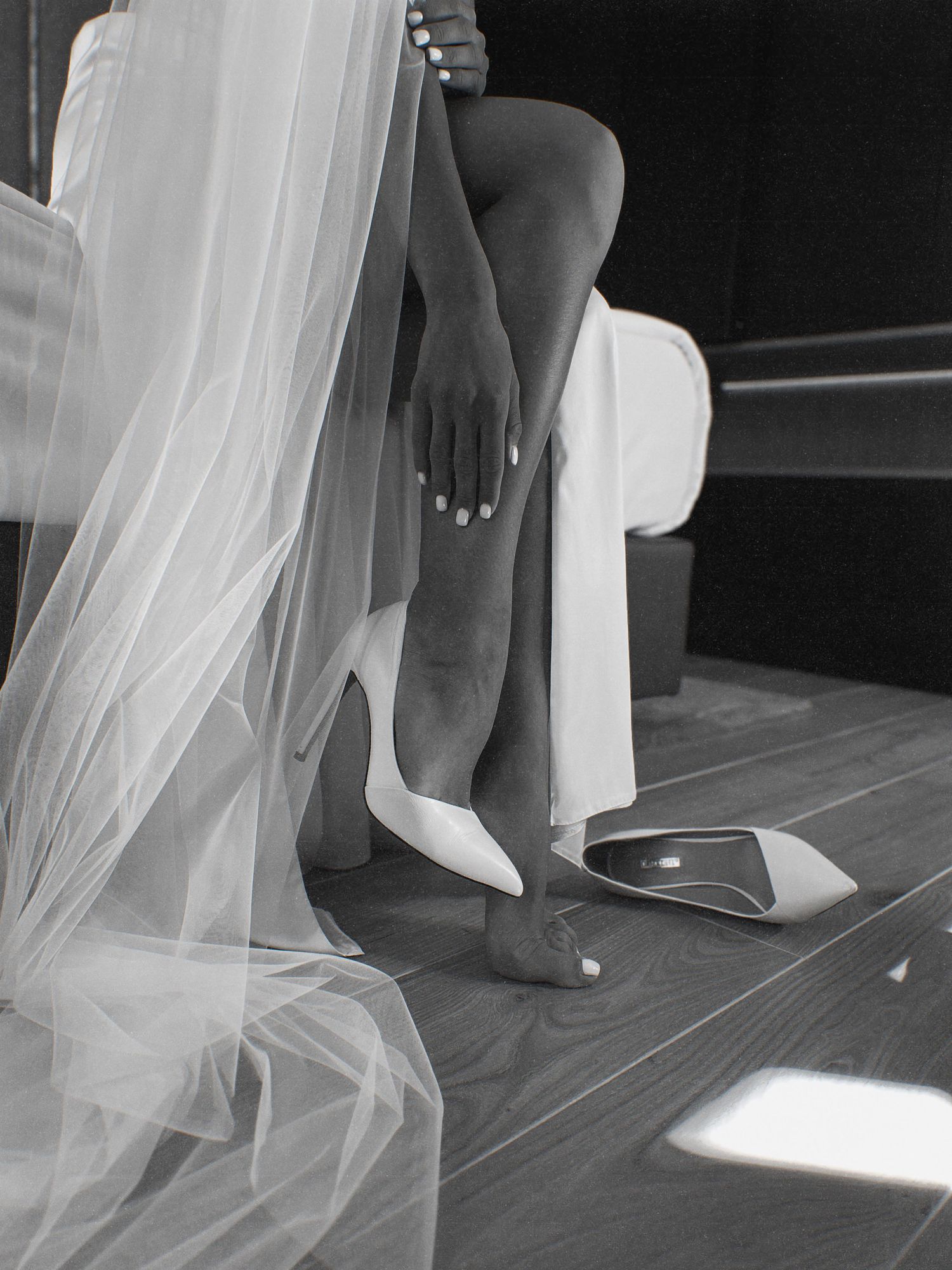 Flowing white wedding veil trailing on wooden floor in artistic composition.
