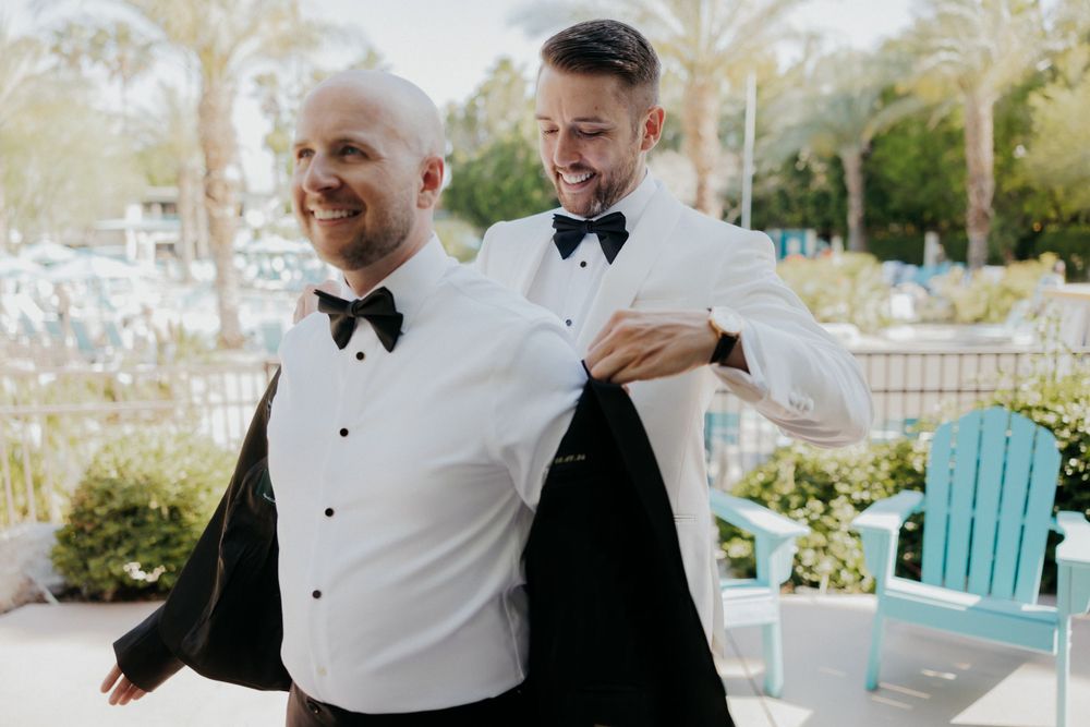 Two people in formal attire embracing and laughing during a special outdoor event.