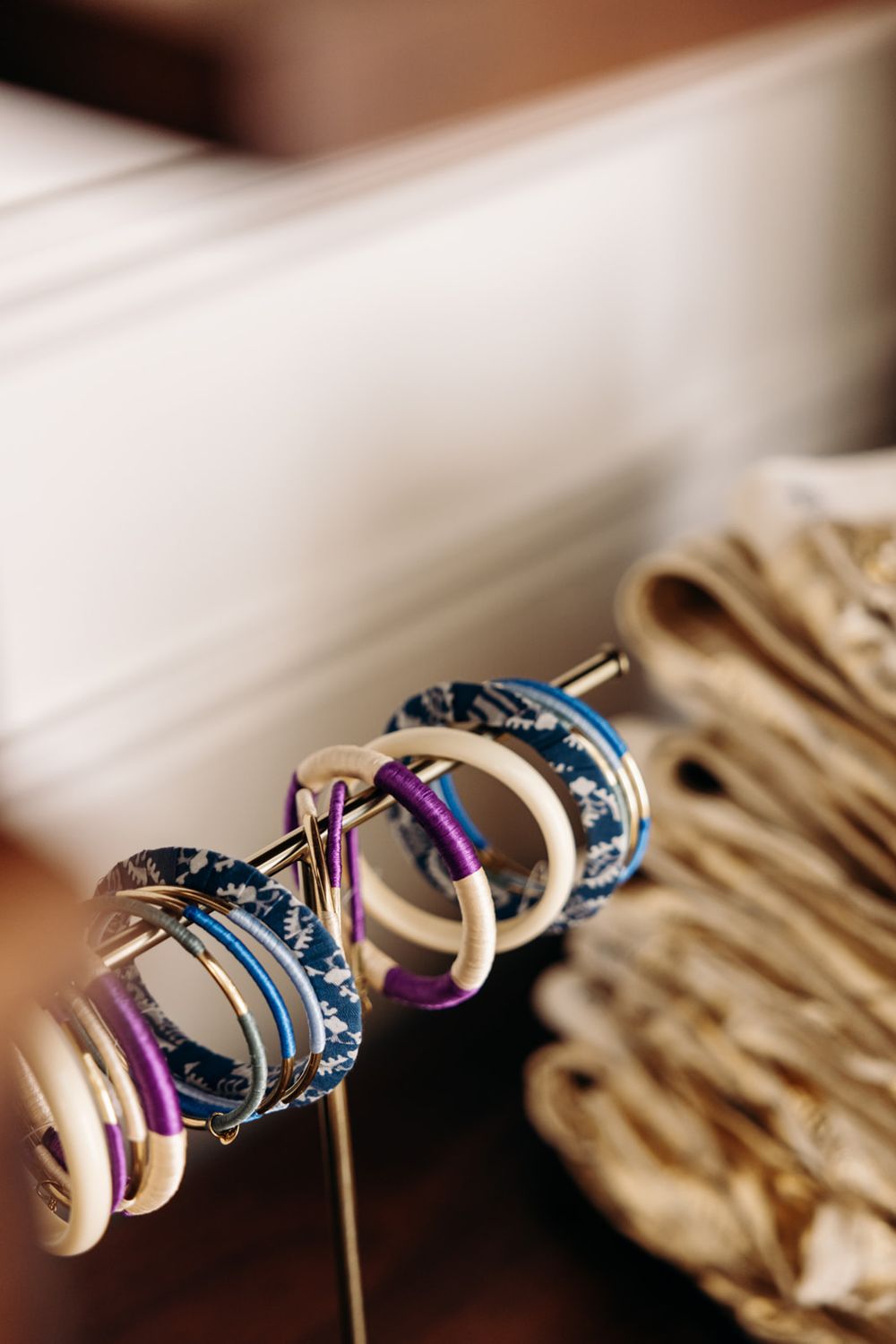 Colorful blue, white, and purple bangles displayed on a stand in a jewelry boutique setting.