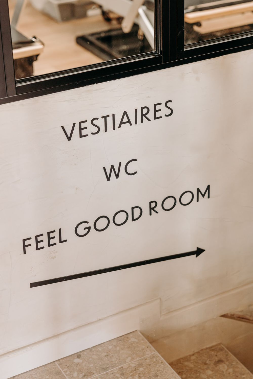 Wall sign directing to Vestiaires, WC, and Feel Good Room with arrow in a modern interior space.