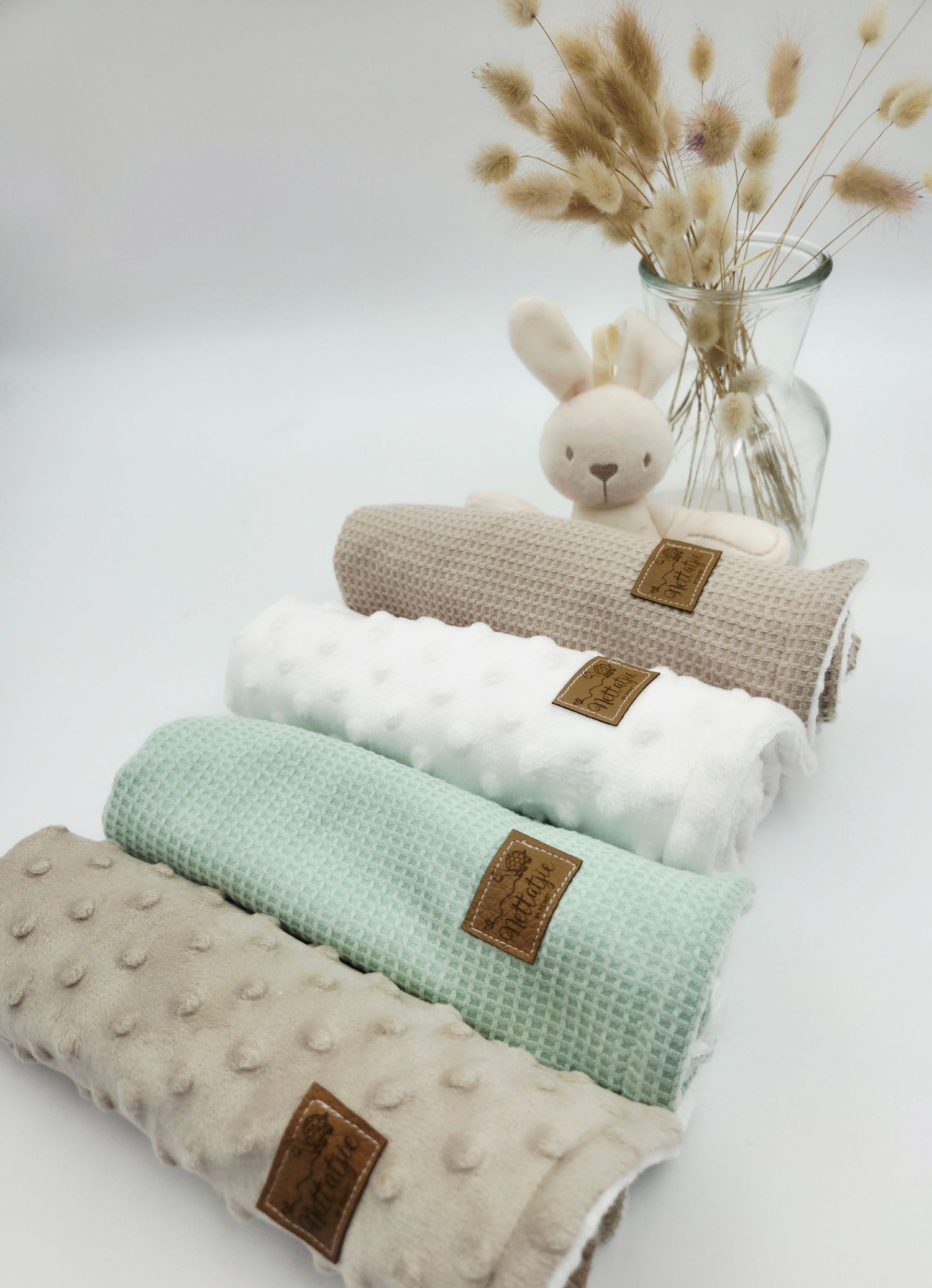 Neutral toned baby blankets with minky fabric and dried pampas grass decoration.