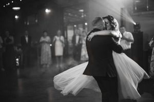 Couple shares their first dance in a dimly lit reception venue.