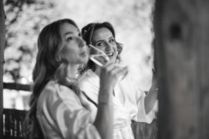 Two people in white shirts share a candid black and white moment on a porch.