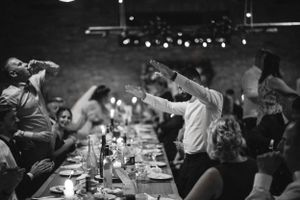 Wedding reception guests celebrating with drinks at a long banquet table.