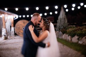 Romantic evening wedding moment under string lights outdoors.