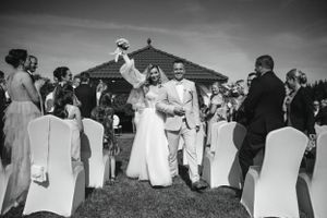 A wedding ceremony celebration on a lawn with white chairs and guests applauding.