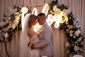A romantic moment under illuminated decor and floral arrangements at a wedding reception.