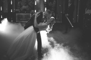 A dramatic black and white photo of a wedding couple's first dance surrounded by atmospheric fog.