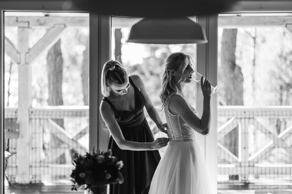 A candid black and white photo of wedding preparations through a window with natural lighting.