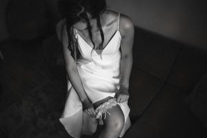 Artistic black and white photo of bride adjusting garter in dramatic lighting.